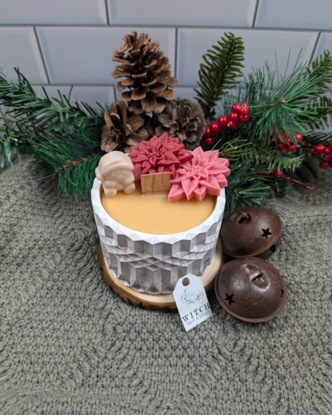 A candle on concrete jar with Poinsettia wax and wax pinguin for decoration.